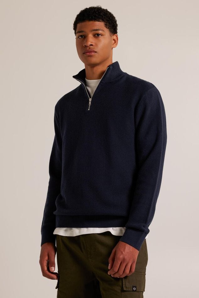 Pull en maille bleu marine pour homme avec demi-fermeture à glissière et design simple pour un look moderne.